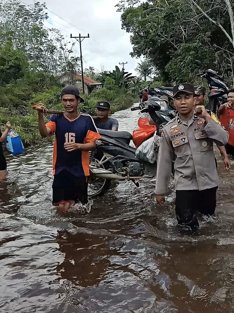 Jalan Lundang Baru Terendam Banjir, Bhabin Polsek Dedai Bantu Warga Pikul Motor